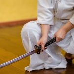 man holding black and gray katana